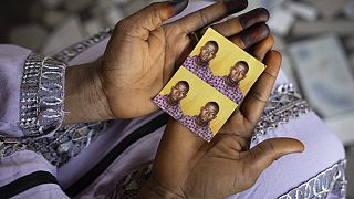 Η Mariama Sylla, αδελφή του Ousmane Sylla, κρατά φωτογραφίες του στο σπίτι τους στο Matoto Bonagui, προάστιο του Conakry, Γουινέα, Δευτέρα 8 Απριλίου 2024.
