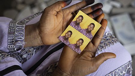 Mariama Sylla, sister of Ousmane Sylla, holds photos of him in their house at Matoto Bonagui, a suburb of Conakry, Guinea, Monday, April 8, 2024.