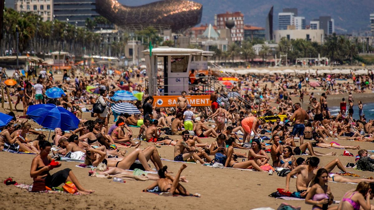 As pessoas apanham banhos de sol na praia em Barcelona, Espanha.