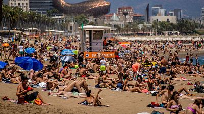 People sunbathe on the beach in Barcelona, Spain.