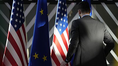 A worker adjusts the US and EU flags at the European Council building in Brussels, 2023.