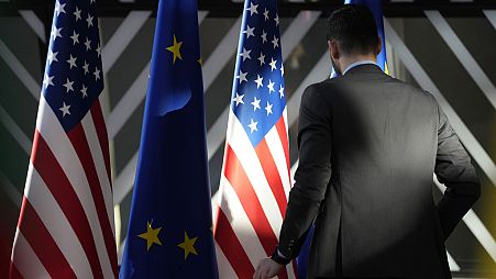 A worker adjusts the US and EU flags at the European Council building in Brussels, 2023.