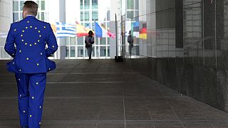 Um homem veste um fato com as cores da UE enquanto caminha à porta do Parlamento Europeu