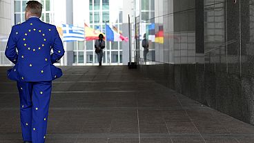 Мужчина в костюме цвета Евросоюза на прогулке у здания Европейского парламента.