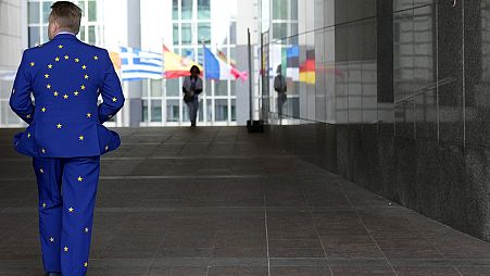 Un uomo indossa un abito con i colori dell'UE mentre cammina fuori dal Parlamento europeo