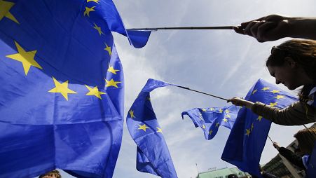 Un hombre viste un traje con los colores de la UE mientras camina frente al Parlamento Europeo