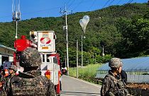 Balloons with trash presumably sent by North Korea, hang on electric wires as soldiers stand guard in Muju, South Korea.