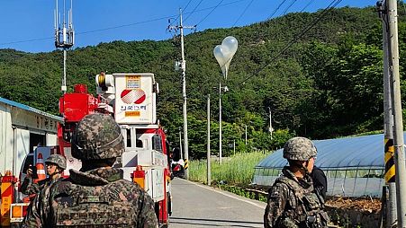 Globos con basura, presumiblemente enviados por Corea del Norte, cuelgan de cables eléctricos mientras soldados montan guardia en Muju, Corea del Sur.