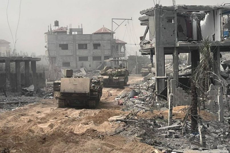 Israeli armoured personnel carriers move past destroyed buildings during a ground operation in the Gaza Strip.