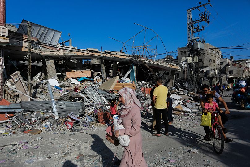 Palestinians walk by the destruction after an Israeli strike in Rafah, Gaza Strip.