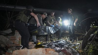 Agenti di polizia portano via un cadavere dopo un attacco missilistico russo che ha colpito un condominio a Kharkiv, 31 maggio 2024