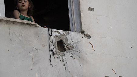 A girl looks out from a window of a building damaged by shrapnels after an Israeli forces raid in the West Bank Jenin refugee camp, Thursday, May 23, 2024. T