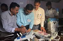 Polling officials check and seal an electronic voting machine before they allow voters to cast their votes at a polling station, India, Saturday, June 1, 2024. 