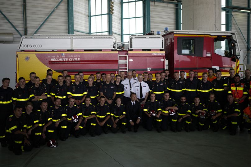 French President Emmanuel Macron (C) poses with rescue workers and firefighters at the Nimes-Garons firefighters air base in 2023