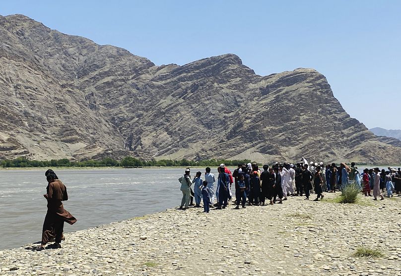 أفغان يقفون على ضفة النهر الذي غرق فيه قارب وأودى بحياة 20 شخصا