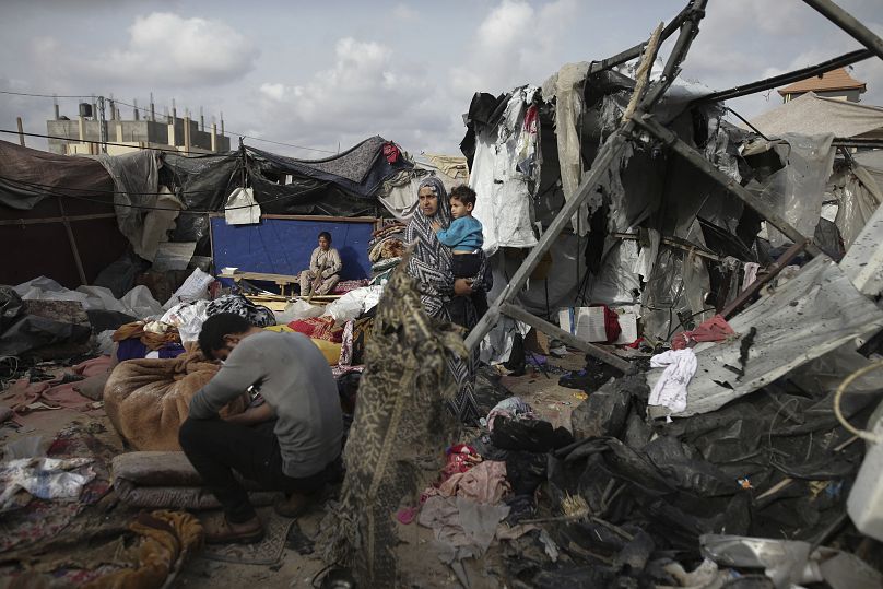 Palestinianos deslocados verificam as suas tendas destruídas por um ataque israelita a oeste de Rafah, 28 de maio de 2024