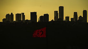 FILE - The sun sets behind high buildings of a financial business area in Istanbul, Turkey, Friday, March 22, 2024. 