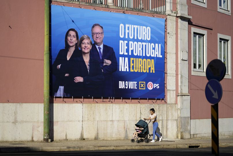A woman pushes a baby stroller past a Socialist Party billboard for the European election, outside the party's headquarters in Lisbon on Friday