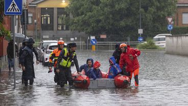 رجال الإطفاء يستخدمون قاربًا لإجلاء امرأة وطفلين بعد أن غمرت المياه بعض الضواحي في ميلانو شمال إيطاليا