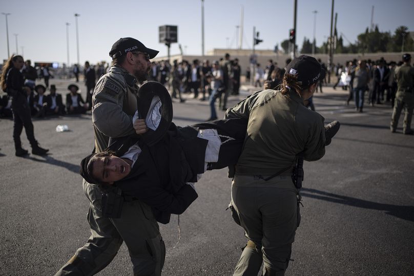 Des officiers de police israéliens retirent un jeune juif ultra-orthodoxe de la rue lors d'une manifestation contre le recrutement de l'armée à Jérusalem, dimanche 2 juin 2024