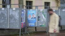 A man walks past a row of campaign boards for the upcoming European election in Versailles west of Paris, Friday, May 31, 2024. 