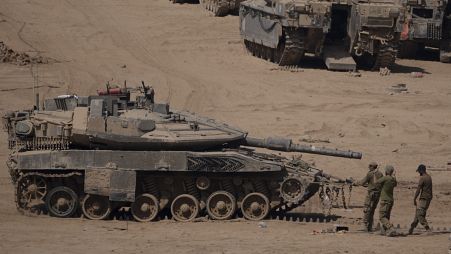 Israeli soldiers work on a tank in a staging area near the Israeli-Gaza border in southern Israel, Monday, June 3, 2024. 