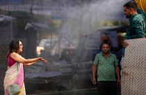 A polling official enjoys a cooling spray of water under intense heat on the eve of the fifth phase of polling in national election in Lucknow, India, Sunday May 19, 2024.