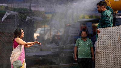 A polling official enjoys a cooling spray of water under intense heat on the eve of the fifth phase of polling in national election in Lucknow, India, Sunday May 19, 2024.