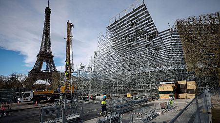 Workers build the stands for the upcoming Olympic Games on the Champ-de-Mars just beside the Eiffel Tower in Paris, 1 April.
