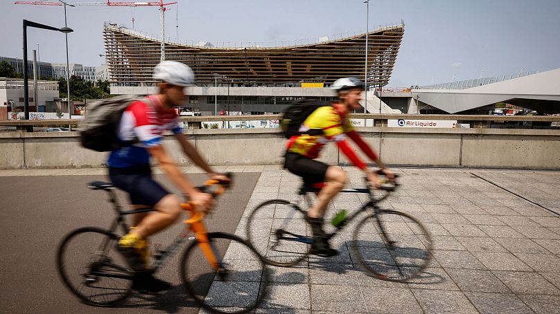 Bisikletçiler, Temmuz 2023'te Paris'in kuzeyindeki Saint-Denis'teki Su Sporları Merkezi yakınlarında bisiklet sürüyor.