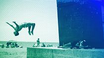 A boy does a back flip at Barcelona's beach, July 2021