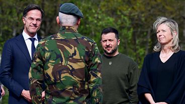 از چپ: مارک روته نخست وزیر هلند، ولودیمیر زلنسکی رئیس جمهوری اوکراین، و کایزا اولونگِرن ‌وزیر دفاع هلند، در بازدید از پایگاه هوایی هلند در ۴ مه ۲۰۲۳ در مقابل یک سرباز.