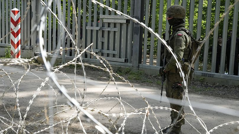 A soldier stands guard by a metal barrier, in Bialowieza Forest, eastern Poland, on Wednesday, May 29, 2024