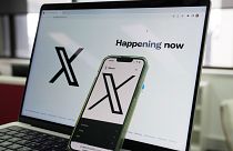 FILE - The opening page of X is displayed on a computer and phone.