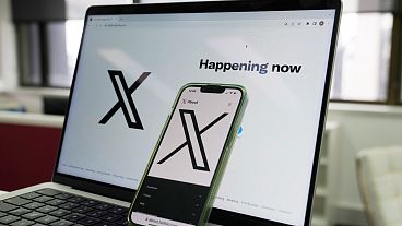 FILE - The opening page of X is displayed on a computer and phone.