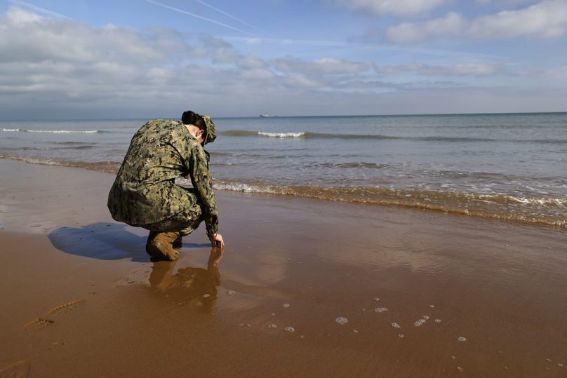 Un soldat américain touche le sable sur la plage d'Omaha Beach, mardi 4 juin 2024.