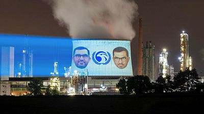 Global Witness projected Al Jaber’s face and findings from its report onto buildings surrounding the Bonn Intersessional on 3 June.