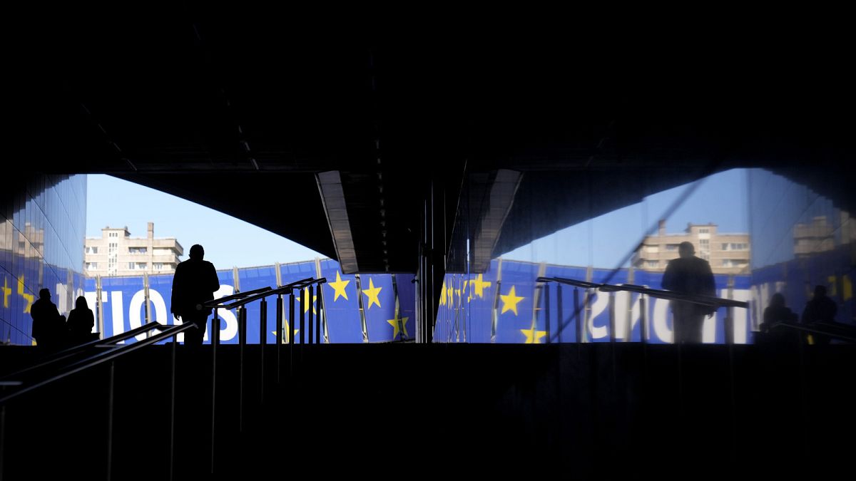 Um homem caminha em direção a um cartaz eleitoral no exterior do Parlamento Europeu, em Bruxelas, na segunda-feira, 29 de abril de 2024. As eleições europeias realizar-se-ão de 6 a 9 de junho de 2024