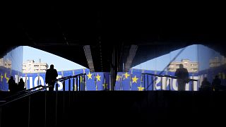Um homem caminha em direção a um cartaz eleitoral no exterior do Parlamento Europeu, em Bruxelas, na segunda-feira, 29 de abril de 2024. As eleições europeias realizar-se-ão de 6 a 9 de junho de 2024