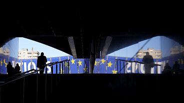 Un uomo cammina verso uno striscione elettorale fuori dal Parlamento europeo a Bruxelles, lunedì 29 aprile 2024. Le elezioni europee si terranno dal 6 al 9 giugno 2024.