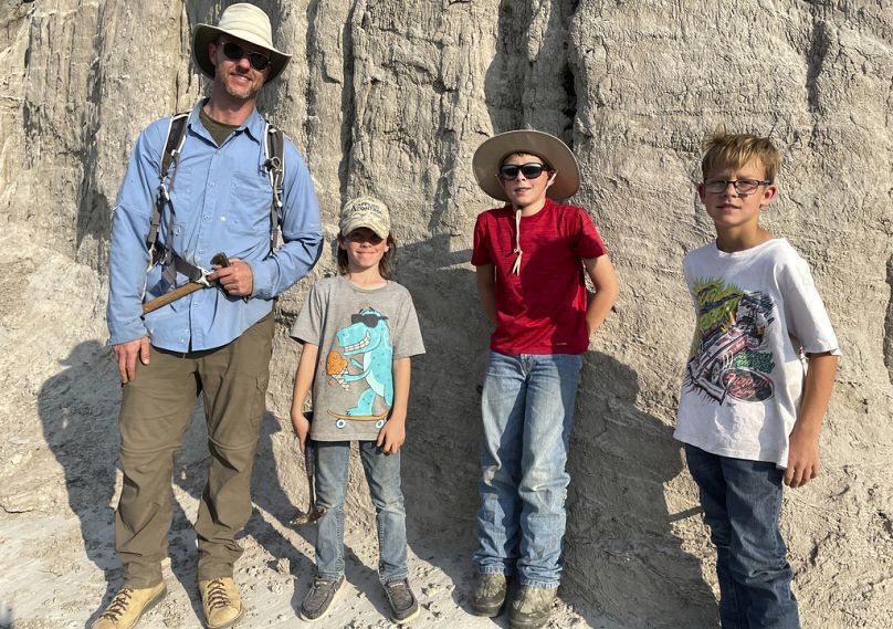 Paleontologist Tyler Lyson poses with young fossil finders Liam Fisher, Jessin Fisher, and Kaiden Madsen on the day they uncovered a juvenile T. rex 