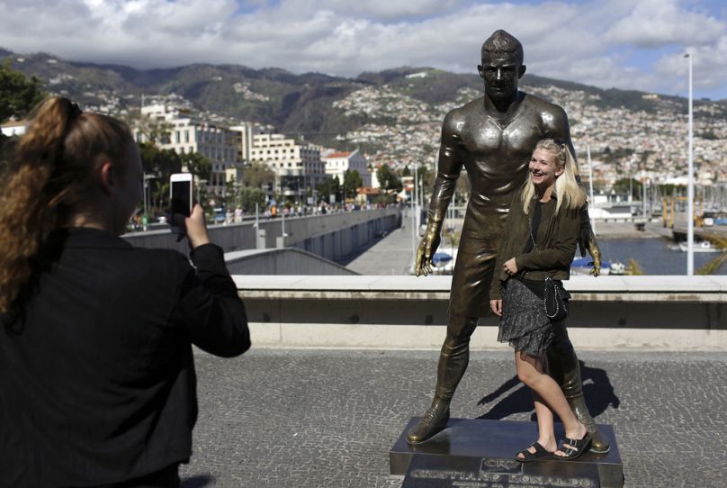 Turisták fotózkodnak Ronaldo szobránál a róla elnevezett funchali (Madeira) repülőtéren