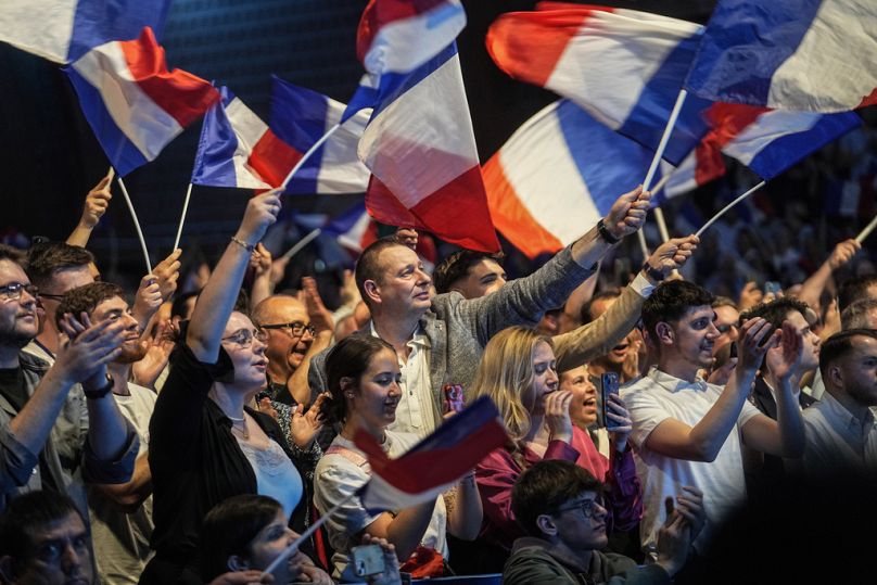 Supporters of the French far right National Rally wave flags during a meeting for the upcoming European elections in Henin-Beaumont, 24 May 2024