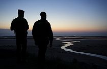 Los policías vigilan el área mientras el sol está a punto de salir sobre la playa de Omaha, cerca de Colleville-sur-Mer, Normandía, el jueves 6 de junio de 2024.