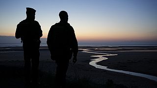 Policemen guard the area during the sun is about to rise over Omaha Beach near Colleville-sur-Mer Normandy, Thursday, June 6, 2024.