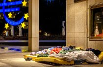 Des sans-abri dorment sous le toit du nouvel opéra à côté de la sculpture de l'Euro dans le centre de Francfort, le 11 mai 2021.