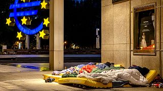 Des sans-abri dorment sous le toit du nouvel opéra à côté de la sculpture de l'Euro dans le centre de Francfort, le 11 mai 2021.