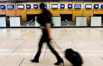 A passenger walks past vacant check-in desks at Paris Orly airport, France, during a strike by French air traffic controllers