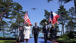 Joe Biden, a primeira-dama Jill Biden; Emmanuel Macron e a sua mulher Brigitte Macron sobem ao palco no 80.º aniversário do Dia D.