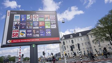 Ποδηλάτες προσπερνούν μια διαφημιστική πινακίδα για τις ευρωπαϊκές εκλογές έξω από το Ναυτικό Μουσείο στο Άμστερνταμ, Ολλανδία, Τετάρτη 5 Ιουνίου 2024.